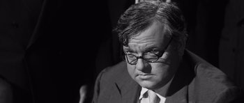 Movie still from “Compulsion” (1959), directed by Richard Fleischer – Black and white photograph of a man in a suit; Close Up shot, Over the shoulder angle