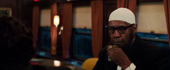 Movie still from “The Equalizer 2” (2018), directed by Antoine Fuqua – A man sitting at a table with a drink in his hand; Close Up shot, Over the shoulder angle