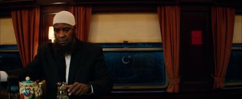 Movie still from “The Equalizer 2” (2018), directed by Antoine Fuqua – A man in a black suit and a white hat; Medium shot, Low angle