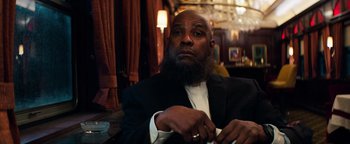 Movie still from “The Equalizer 2” (2018), directed by Antoine Fuqua – A man in a suit and beard sitting at a table in a restaurant; Close Up shot, Low angle