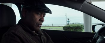 Movie still from “The Equalizer 2” (2018), directed by Antoine Fuqua – A man wearing a hat sitting in the back of a car; Close Up shot, Over the shoulder angle