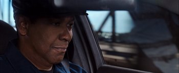 Movie still from “The Equalizer 2” (2018), directed by Antoine Fuqua – A man sitting in the driver's seat of a car; Close Up shot, Over the shoulder angle