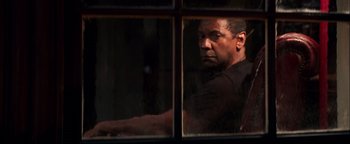 Movie still from “The Equalizer 2” (2018), directed by Antoine Fuqua – A man looking out of a window at night; Medium shot, Low angle