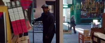 Movie still from “The Equalizer 2” (2018), directed by Antoine Fuqua – A man wearing a hat standing in front of a closed sign; Medium shot, Over the shoulder angle