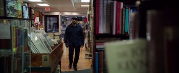 Movie still from “The Equalizer 2” (2018), directed by Antoine Fuqua – A man walking in a library next to some books; Medium shot, Low angle