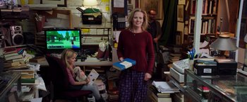 Movie still from “The Equalizer 2” (2018), directed by Antoine Fuqua – A woman holding a book in a cluttered room; Wide shot, Over the shoulder angle