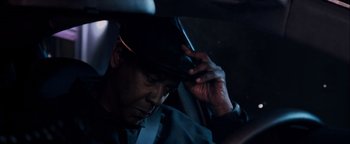 Movie still from “The Equalizer 2” (2018), directed by Antoine Fuqua – A man sitting in the back seat of a car while holding a cell phone to his head; Close Up shot, Low angle