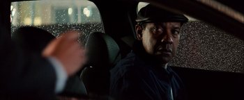 Movie still from “The Equalizer 2” (2018), directed by Antoine Fuqua – A man sitting in the back seat of a car; Close Up shot, Over the shoulder angle