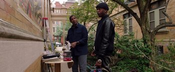 Movie still from “The Equalizer 2” (2018), directed by Antoine Fuqua – Two men standing next to each other in a yard; Medium shot, Over the shoulder angle