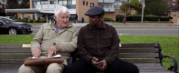 Movie still from “The Equalizer 2” (2018), directed by Antoine Fuqua – Two older men sitting on a park bench talking; Medium shot, Over the shoulder angle