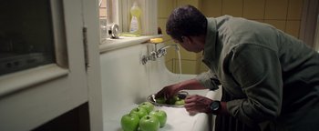 Movie still from “The Equalizer 2” (2018), directed by Antoine Fuqua – A man washing green apples in a kitchen sink; Medium shot, Over the shoulder angle
