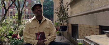 Movie still from “The Equalizer 2” (2018), directed by Antoine Fuqua – A man sitting on the ground holding a book in his hands; Medium shot, Over the shoulder angle