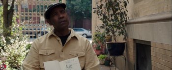 Movie still from “The Equalizer 2” (2018), directed by Antoine Fuqua – An older man holding an open book while standing in front of a tree; Close Up shot, Over the shoulder angle