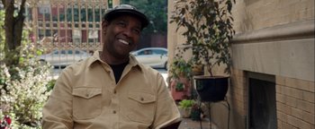 Movie still from “The Equalizer 2” (2018), directed by Antoine Fuqua – A man wearing a hat smiling for the camera; Medium shot, Over the shoulder angle