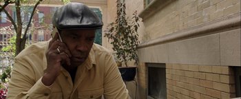 Movie still from “The Equalizer 2” (2018), directed by Antoine Fuqua – A man wearing a black hat and a tan shirt; Close Up shot, Low angle