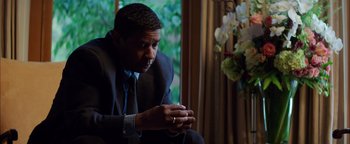Movie still from “The Equalizer 2” (2018), directed by Antoine Fuqua – A man in a suit sitting in front of a window; Close Up shot, Low angle