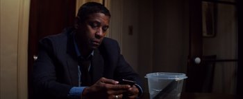 Movie still from “The Equalizer 2” (2018), directed by Antoine Fuqua – A man sitting at a table looking at his cell phone; Close Up shot, Low angle