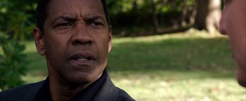 Movie still from “The Equalizer 2” (2018), directed by Antoine Fuqua – A man's face in a grassy area; Close Up shot, Over the shoulder angle
