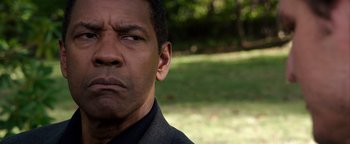 Movie still from “The Equalizer 2” (2018), directed by Antoine Fuqua – A man's face in a grassy area; Close Up shot, Over the shoulder angle