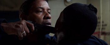 Movie still from “The Equalizer 2” (2018), directed by Antoine Fuqua – A man holding a knife to his mouth while holding a cell phone to his ear; Close Up shot, Over the shoulder angle