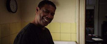 Movie still from “The Equalizer 2” (2018), directed by Antoine Fuqua – A man smiling for the camera in front of a tiled wall; Close Up shot, Low angle
