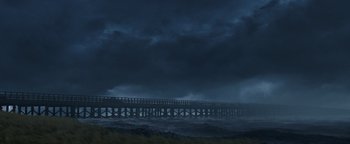 Movie still from “The Equalizer 2” (2018), directed by Antoine Fuqua – A pier is in the middle of the ocean under a cloudy sky; Extreme Wide shot, Low angle