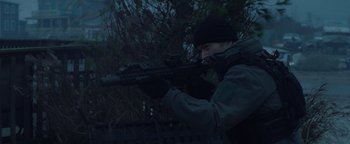 A man with a rifle in a wooded area