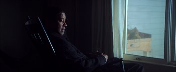 Movie still from “The Equalizer 2” (2018), directed by Antoine Fuqua – A man sitting in front of a window in a dark room; Medium shot, Low angle