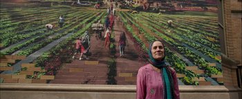 Movie still from “The Equalizer 2” (2018), directed by Antoine Fuqua – A woman standing in front of a painting of people in a field; Medium shot, Low angle