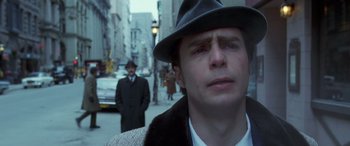 Movie still from “Confessions of a Dangerous Mind” (2002), directed by George Clooney – A man wearing a hat and a fur coat on the street; Close Up shot, Low angle