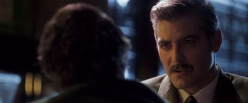 Movie still from “Confessions of a Dangerous Mind” (2002), directed by George Clooney – A man with a mustache in a suit; Close Up shot, Over the shoulder angle