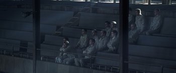 Movie still from “Confessions of a Dangerous Mind” (2002), directed by George Clooney – A group of men sitting in bleachers at a sporting event; Wide shot, High angle