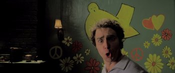 Movie still from “Confessions of a Dangerous Mind” (2002), directed by George Clooney – A young man with his mouth wide open in front of a wall with flowers; Close Up shot, Low angle