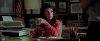 Movie still from “Confessions of a Dangerous Mind” (2002), directed by George Clooney – A woman sitting at a table holding a glass of water; Medium shot, Over the shoulder angle