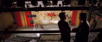 Movie still from “Confessions of a Dangerous Mind” (2002), directed by George Clooney – A man standing in front of a stage; Extreme Wide shot, High angle