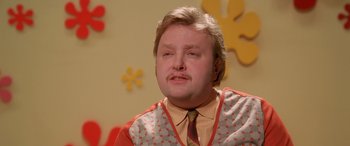 Movie still from “Confessions of a Dangerous Mind” (2002), directed by George Clooney – A man with a beard and mustache wearing an orange and red vest; Close Up shot, Low angle