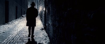 Movie still from “Confessions of a Dangerous Mind” (2002), directed by George Clooney – A man standing in the dark in front of a brick wall; Wide shot, Low angle