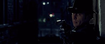 Movie still from “Confessions of a Dangerous Mind” (2002), directed by George Clooney – A man holding a gun while standing in a dark room; Close Up shot, Over the shoulder angle