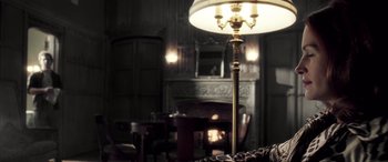 Movie still from “Confessions of a Dangerous Mind” (2002), directed by George Clooney – A dimly - lit living room with a fireplace; Medium shot, Over the shoulder angle