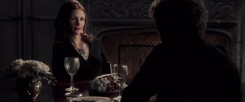 Movie still from “Confessions of a Dangerous Mind” (2002), directed by George Clooney – A woman sitting at a dinner table with a man; Medium shot, Over the shoulder angle