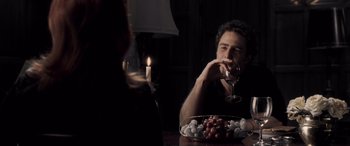 Movie still from “Confessions of a Dangerous Mind” (2002), directed by George Clooney – A man sitting in front of a bowl of grapes; Medium shot, Over the shoulder angle