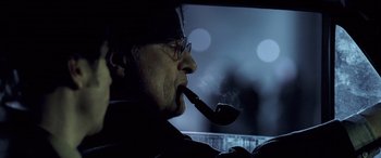 Movie still from “Confessions of a Dangerous Mind” (2002), directed by George Clooney – A man smoking a pipe while sitting in a car; Close Up shot, Low angle
