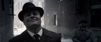 Movie still from “Confessions of a Dangerous Mind” (2002), directed by George Clooney – A black and white photo of a man wearing a hat; Close Up shot, Low angle
