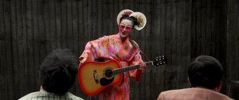 Movie still from “Confessions of a Dangerous Mind” (2002), directed by George Clooney – A woman in a kimono holding a guitar; Medium shot, Over the shoulder angle
