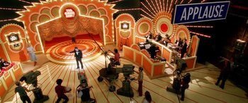 Movie still from “Confessions of a Dangerous Mind” (2002), directed by George Clooney – A group of people in a room with lights on; Extreme Wide shot, High angle