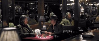 Movie still from “Confessions of a Dangerous Mind” (2002), directed by George Clooney – Two people are sitting at a table in a restaurant; Medium shot, High angle