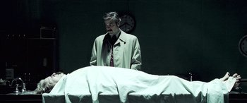 Movie still from “Confessions of a Dangerous Mind” (2002), directed by George Clooney – A man standing in front of a bed in a dark room; Medium shot, Low angle