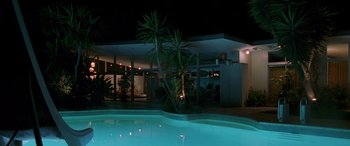 Movie still from “Confessions of a Dangerous Mind” (2002), directed by George Clooney – A swimming pool lit up at night with a palm tree; Extreme Wide shot, Low angle