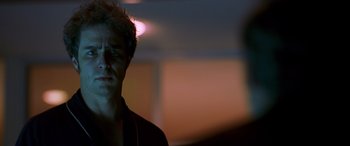 Movie still from “Confessions of a Dangerous Mind” (2002), directed by George Clooney – A man standing in a room with a light shining on him; Close Up shot, Over the shoulder angle