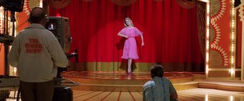 Movie still from “Confessions of a Dangerous Mind” (2002), directed by George Clooney – A woman in a pink dress on a stage; Wide shot, Low angle